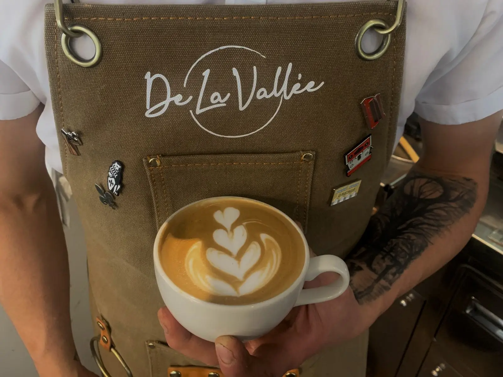 Cappuccino con latte art e grembiule De la Vallée